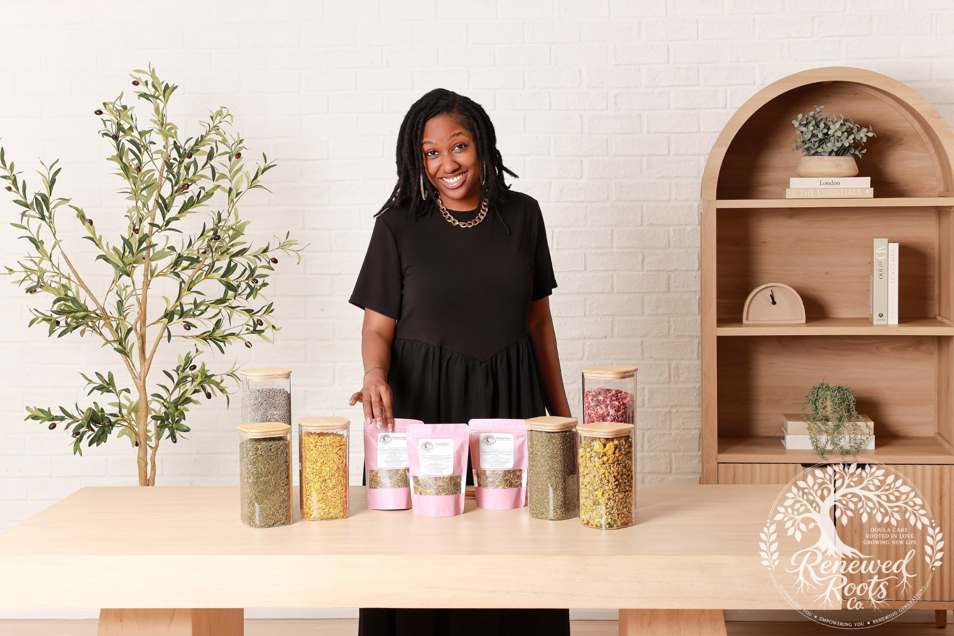 Eliana beside jars of herbs and Renewed Roots wellness blends